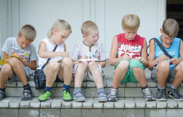 Kinder die auf Stufen sitzen und etwas basteln.
